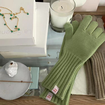 Flat lay of gray knitted gloves with ribbed long sleeves on wooden surface