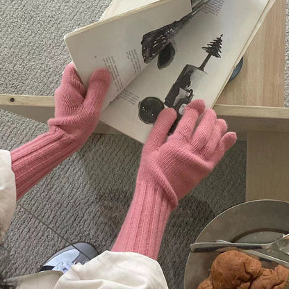 Model wearing gray knitted gloves with sleeves paired with winter coat