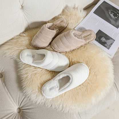 Pair of brown corduroy slippers with soft lining on a wooden surface