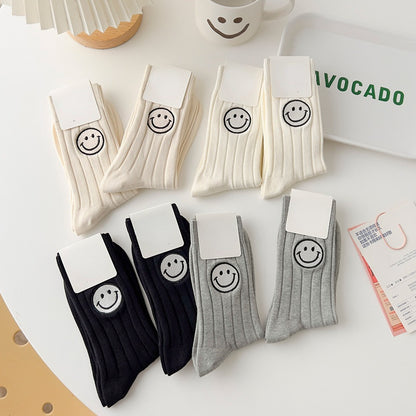 Four pairs of colorful socks each featuring a different happy face design